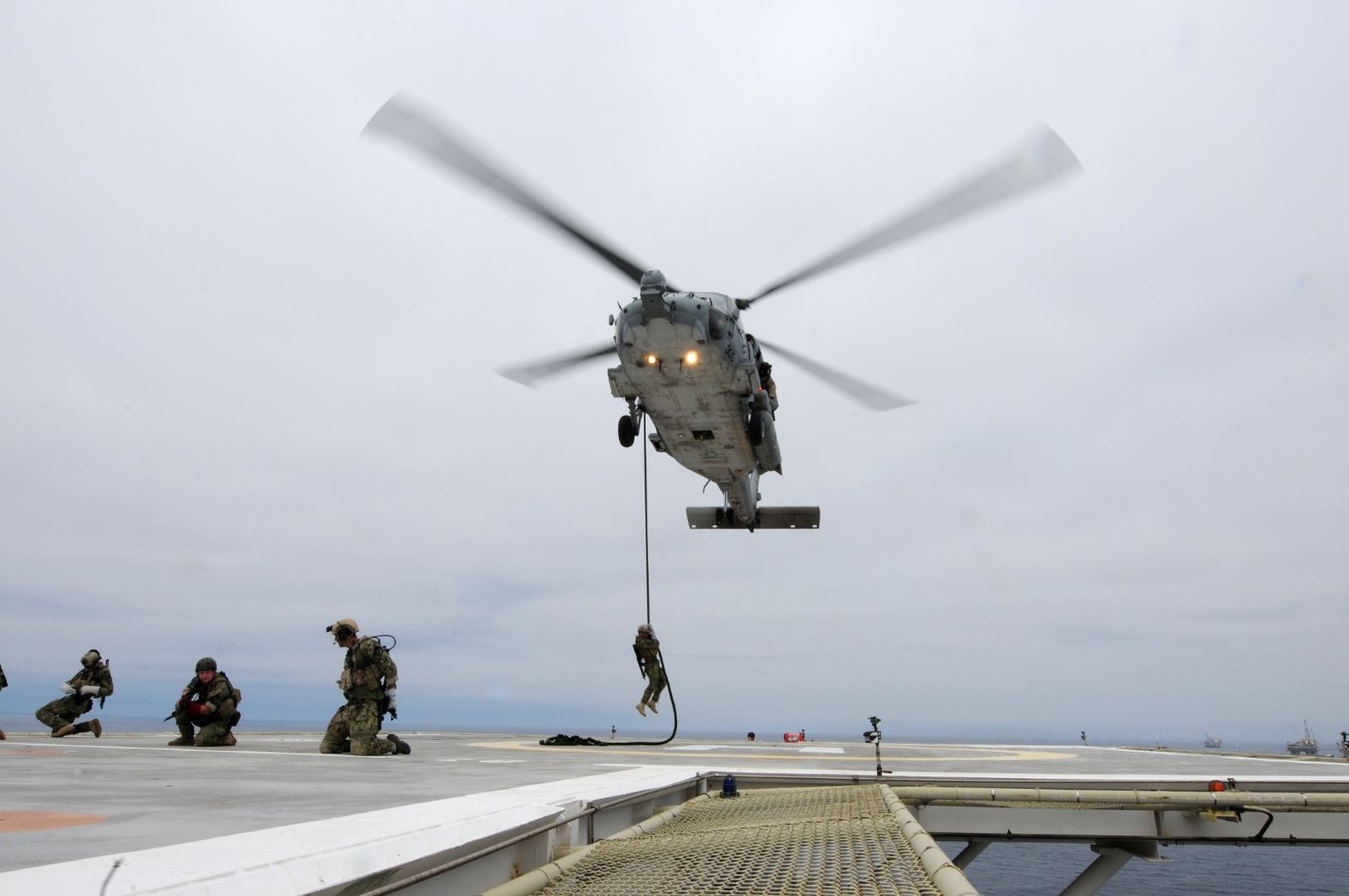 Operators fast roping from a helicopter onto a deck