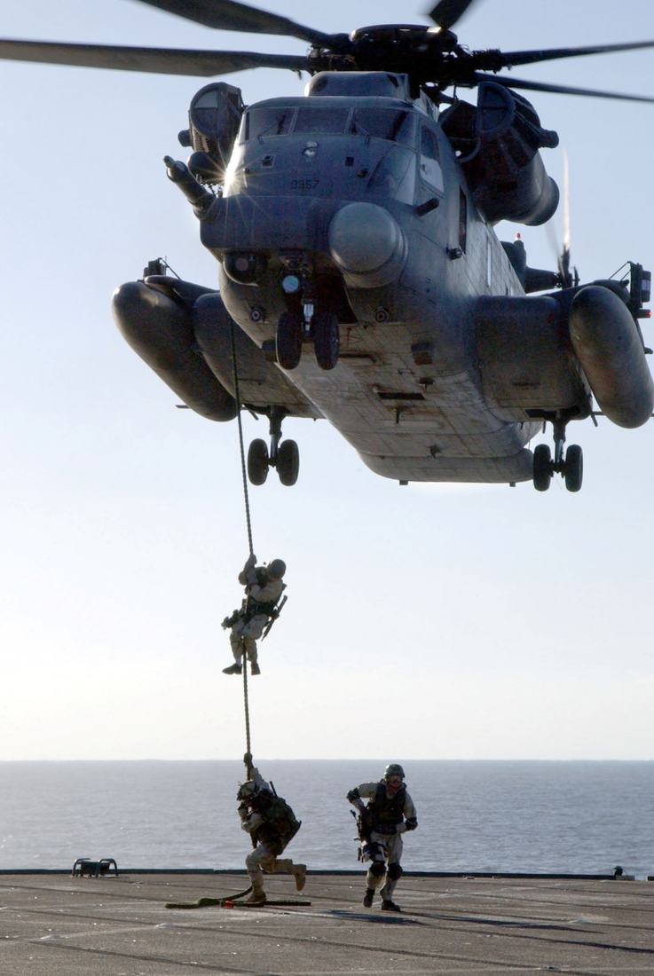Operators fast roping from a helicopter onto a ship deck