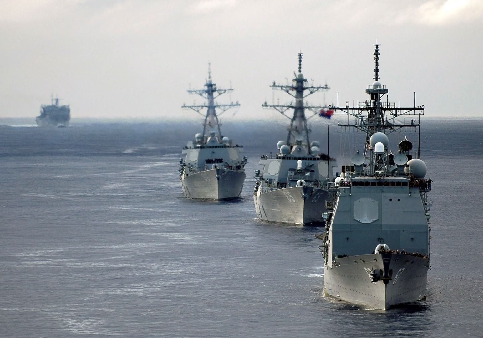 Navy vessels steaming in formation on open water