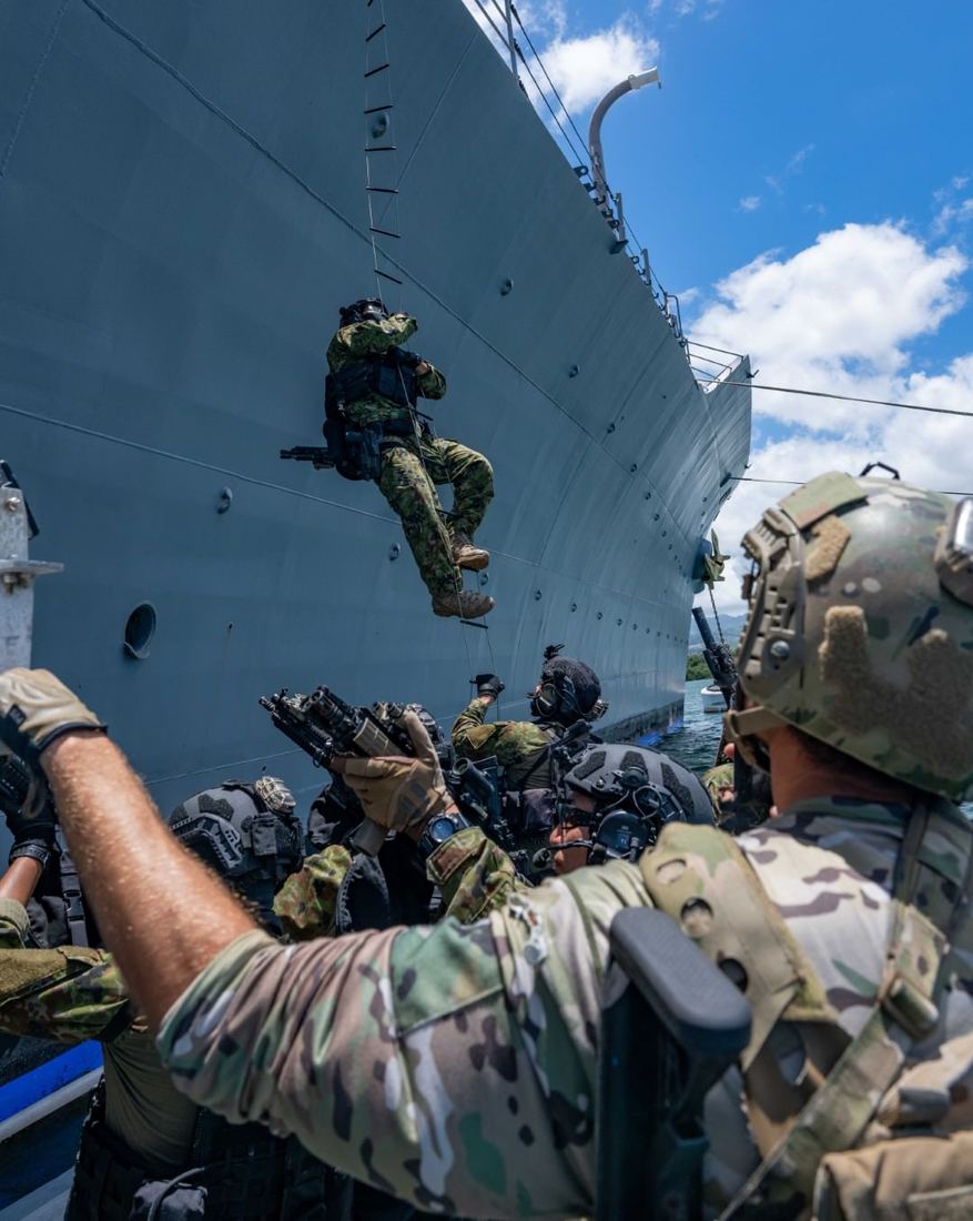 Operators helping a teammate up a ladder from a small boat