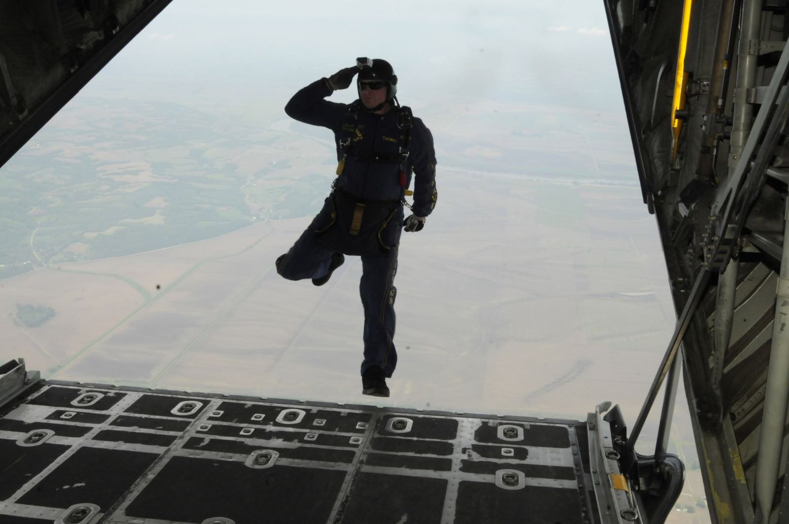 An operator silhouetted on an aircraft ramp, rendering a salute before the jump