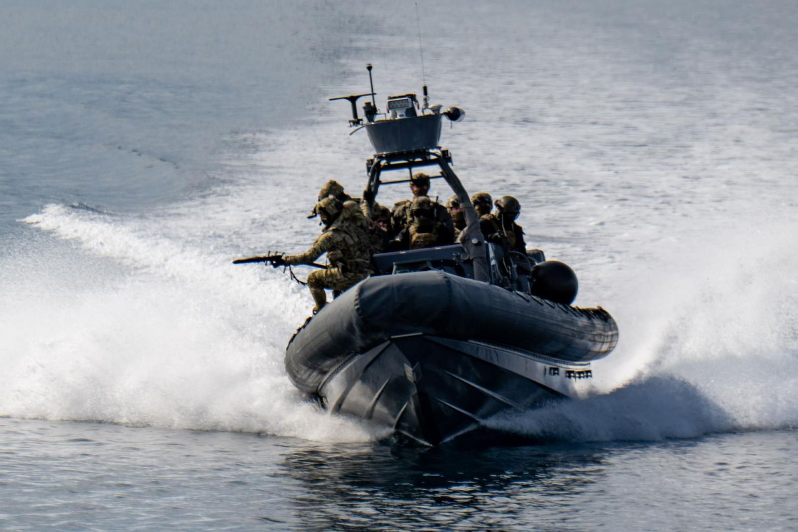 A rigid hull inflatable boat running at speed with its crew aboard