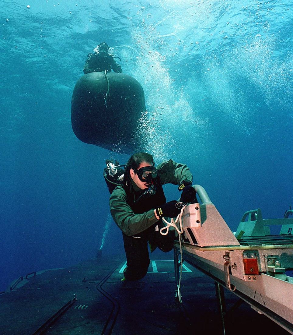 Divers working alongside a submersible delivery vehicle