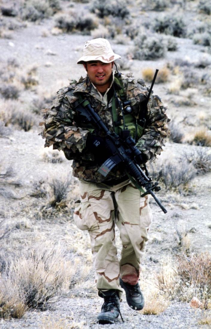 A Naval Special Warfare operator moving across open terrain