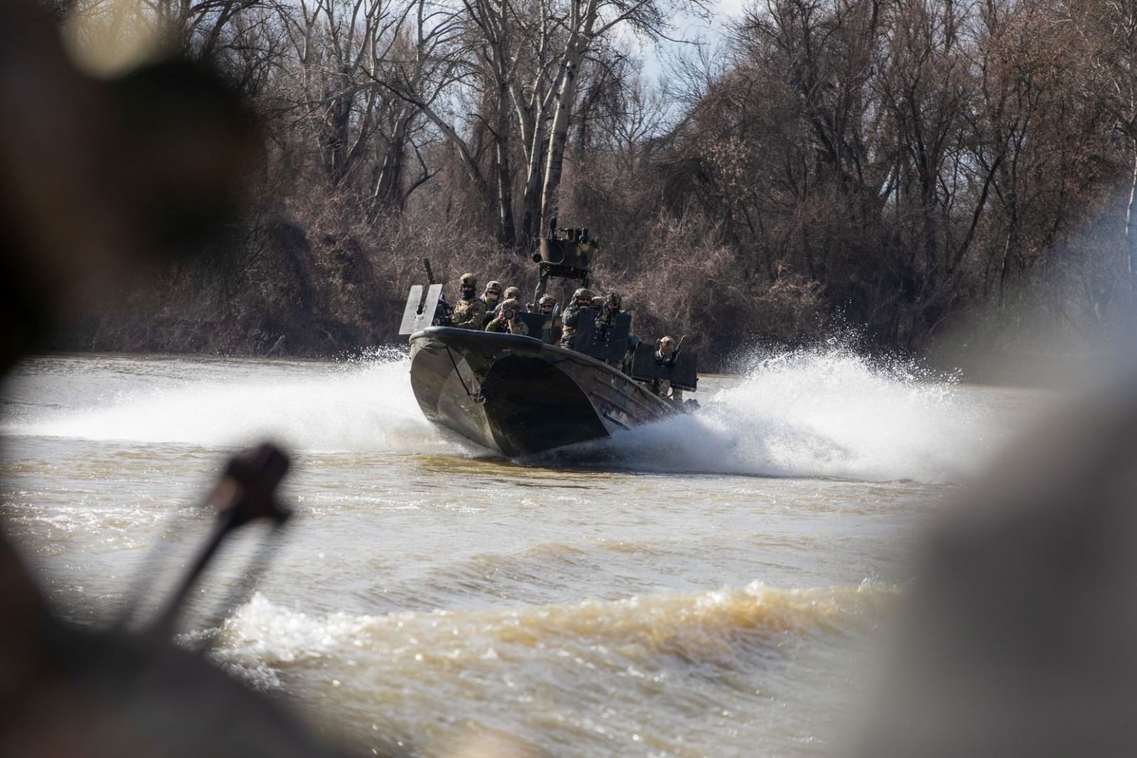 A special warfare combatant craft running a narrow river channel